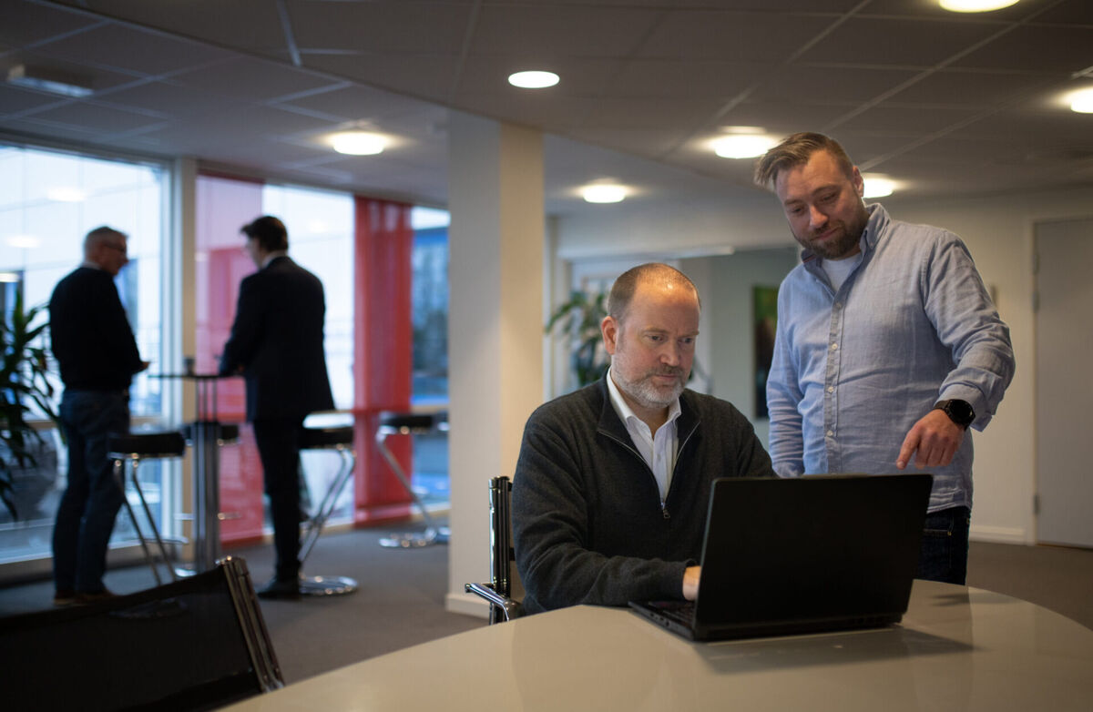 Universell utforming er ikke en sjekkliste. Det er et valg om hvem du inkluderer når du designer, skriver Kay Telle Hoel. Foto: Didrik Vestaberg (bildet er hentet fra Digitelles nettsted) To menn ved en PC, og den ene står og peker mot skjermen.