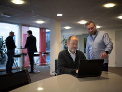 Universell utforming er ikke en sjekkliste. Det er et valg om hvem du inkluderer når du designer, skriver Kay Telle Hoel. Foto: Didrik Vestaberg (bildet er hentet fra Digitelles nettsted) To menn ved en PC, og den ene står og peker mot skjermen.