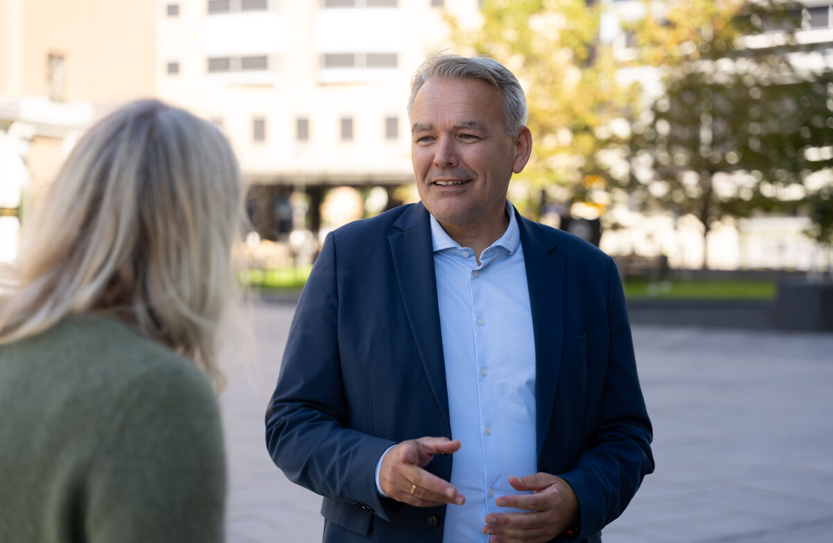 Administrerende direktør Jan Hjelle i Husbanken skal lede det nye direktoratet. Foto: Husbanken Bildet vis Jan Hjelle utendørs i samtale med en kvinne som vi ser bakfra.