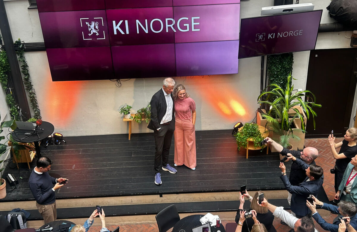 Digitaliserings- og forvaltningsminister Karianne Tung (Ap) lanserer satsingen sammen med direktøren for KI Norge, Hans Christian Holte. Foto: DFD En kvinne og en mann på en scene. Mange fotografer i front. Bildet er tatt ovenfra.
