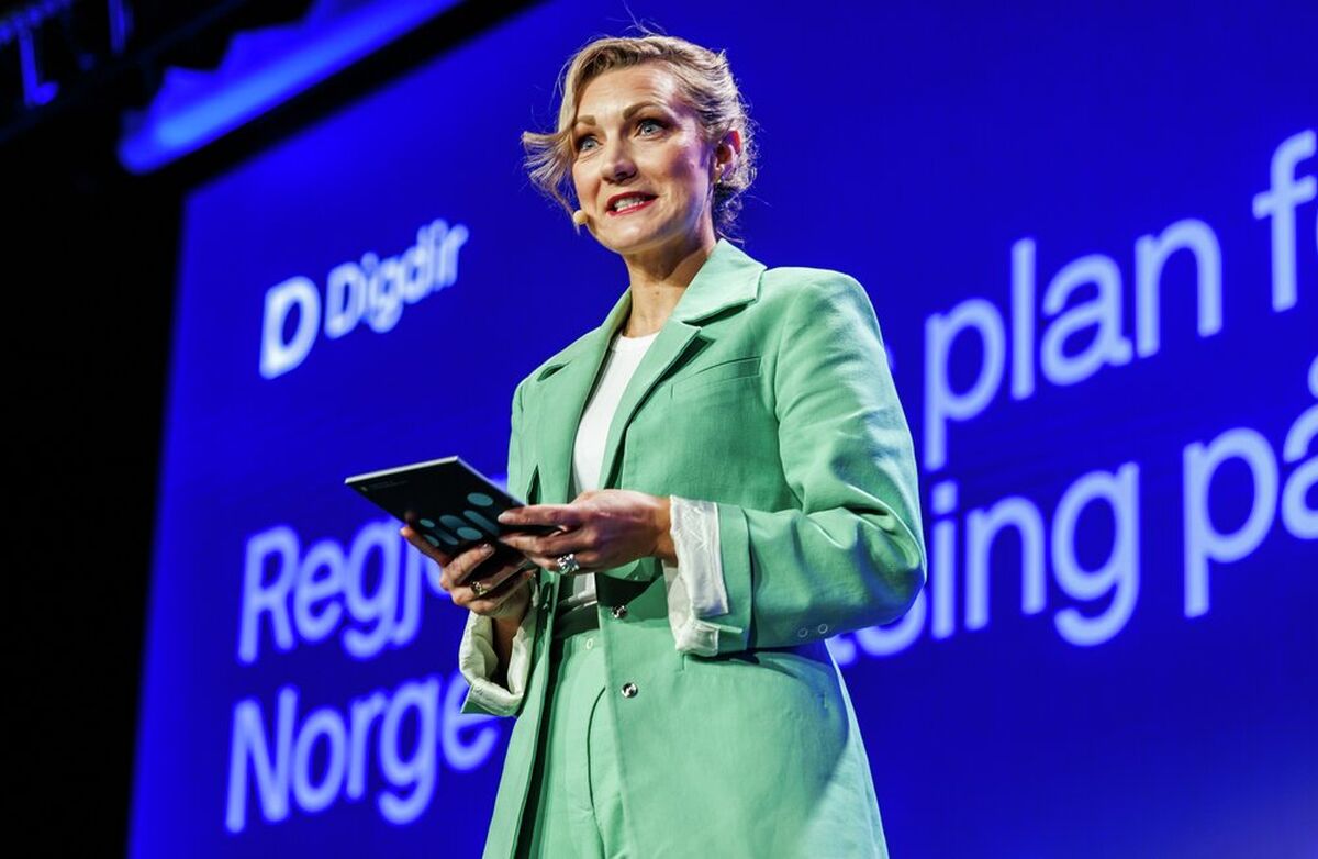 TUNG: Det er alltid en fare i å henge seg opp i historiske analogier, skriver Arild Haraldsen om digitaliseringsminister Karianne Tungs åpningstale under Digitaliseringskonferansen 2026. Foto: Kilian Munch, Digitaliseringskonferansen Lys kvinne i grønn drakt på scenen.
