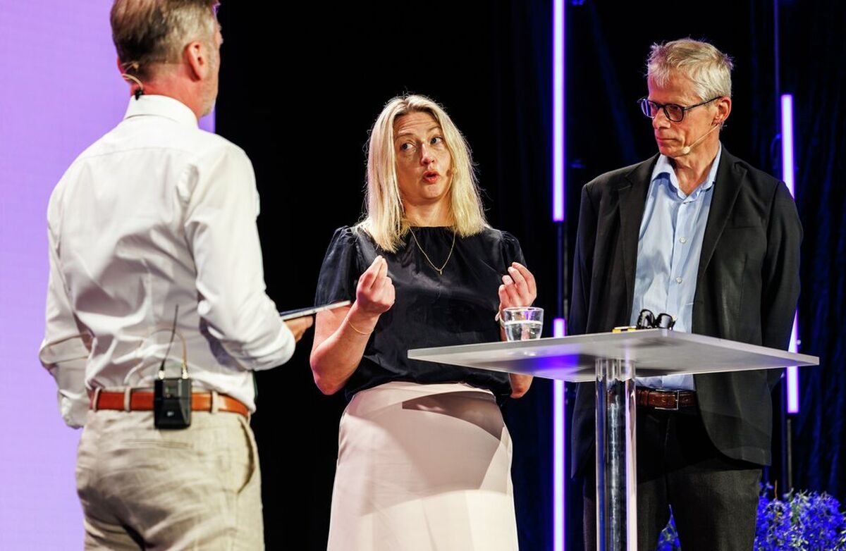 To menn og en kvinne på scenen i samtale.