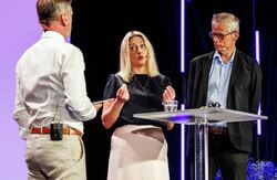 Gjennom samtalen tegnet Holte og Broomfield et bilde av KI Norge som en enhet som skal bidra med både tempo og trygghet. Den skal lytte, samle kunnskap, utvikle veiledning, koble miljøer og sette vanskelige spørsmål på dagsorden. Foto: Kilian Munch, Digitaliseringskonferansen To menn og en kvinne på scenen i samtale.