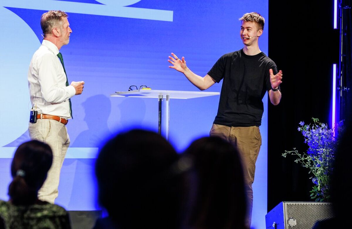 Erik Nymo Bohnes hovedbudskap var at KI endrer hva slags kompetanse samfunnet trenger. Formell utdanning er fortsatt viktig, men den må kombineres med praktisk erfaring, teknologiforståelse og evnen til å arbeide tett på nye verktøy. Foto: Kilian Munch Ung engasjert mann på scenen sammen med programlederen