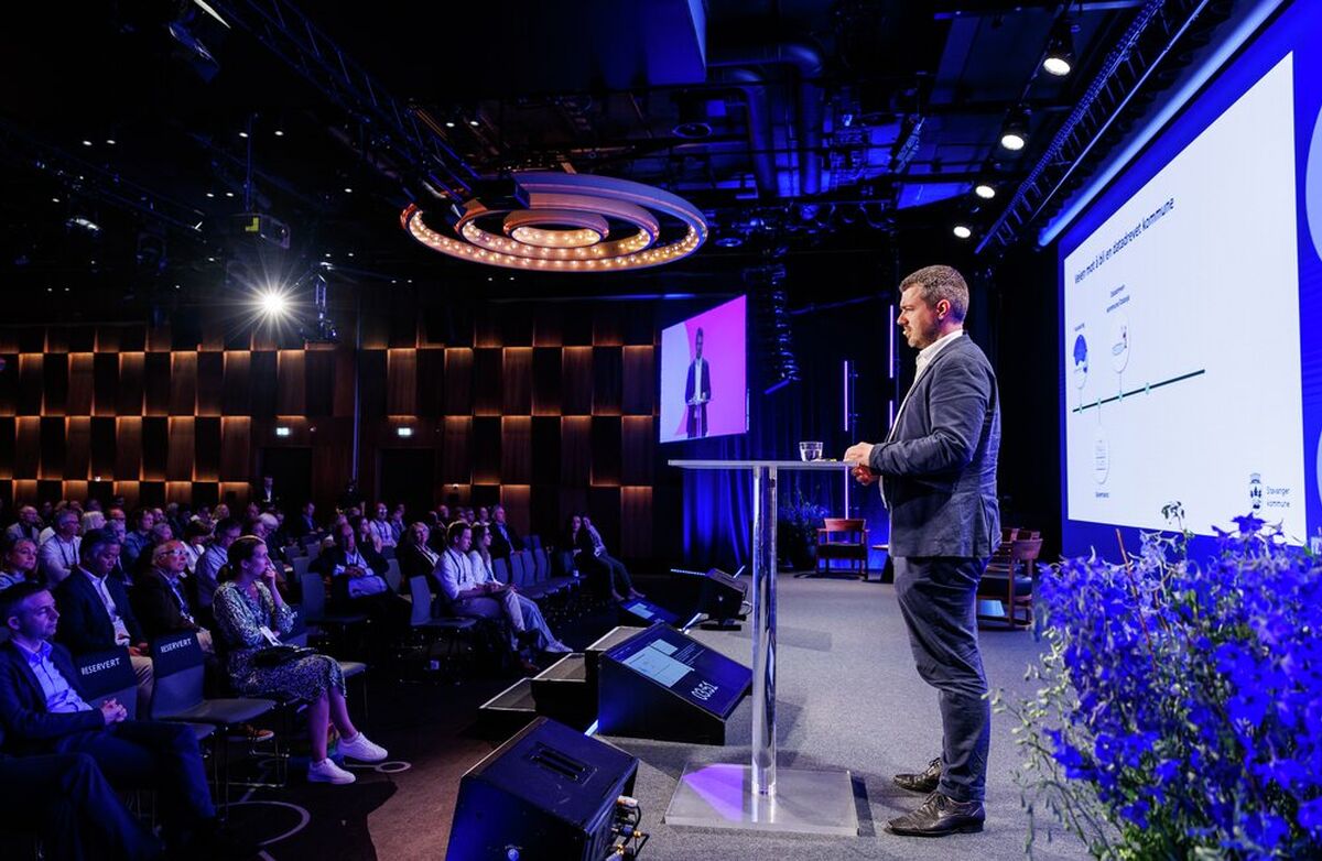 Selv om Stavanger er kåret til årets KI-kommune, understreket Lars Christian Tufte at kommunen ikke er ferdig. Foto: Kilian Munch, Digitaliseringskonferansen Mann på scenen, sett fra avstand og på siden.