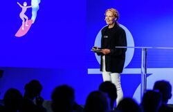 Maria Therese Sanna understreket at KI Oslo ikke består av en lang rekke løsrevne prosjekter. – Dette er ikke 100 pluss initiativer og prosjekter. Det er bydeler, virksomheter og etater som bygger på samme grunn: et felles økosystem, sa hun. Foto: Kilian Munch, Digitaliseringskonferansen Relativt ung kvinne på scenen. Blondt, langt hår. Blå bakgrunn.