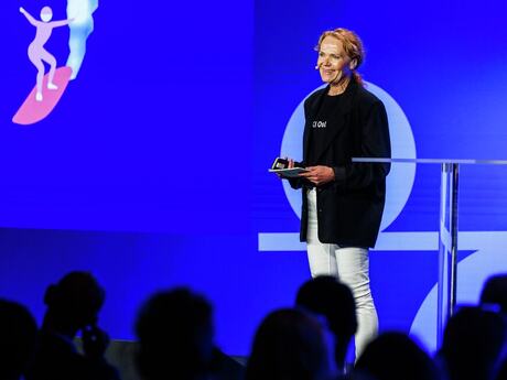 Relativt ung kvinne på scenen. Blondt, langt hår. Blå bakgrunn.