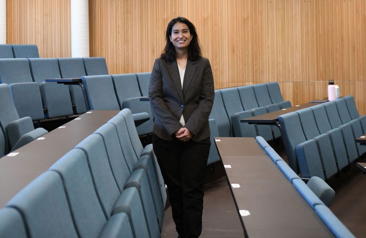 Pallavi Prabhakar forsker på hva som skal til for at offentlige tiltak faktisk gir bedre resultater – fra kontantoverføringer og støtte til foreldre til informasjon om hvordan myndighetene presterer. Hun disputerer ved NHH 28. august. Foto: Sigrid Folkestad Ung kvinne står blant tomme stoler i et forelesningatrium.
