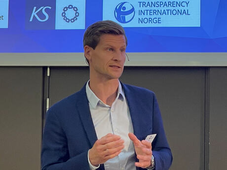 Petter Skjærvø, korrupsjonsforebygger i Økokrim, holder innlegg på Etikkonferansen. På skjermen bak ham vises blant annet logoene til KS og Transparency International Norge.