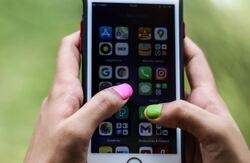 Med den kommende digitale lommeboka kan du samle dei viktigaste dataene om deg i éin app, og med full kontroll på kva og kven du vil dele informasjon med. Foto: Ravi Roshan / Pexels To hender som holder en mobil, og vi ser tommelfingerneglene der den venstre er rosa og den høyre grønn. I bakgrunnen er det dust grønt.