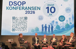 Konferansier og paneldeltakerne sitter på scenn. Bakgrunnsbildet på skjermen viser DSOP med tekst og symboler.